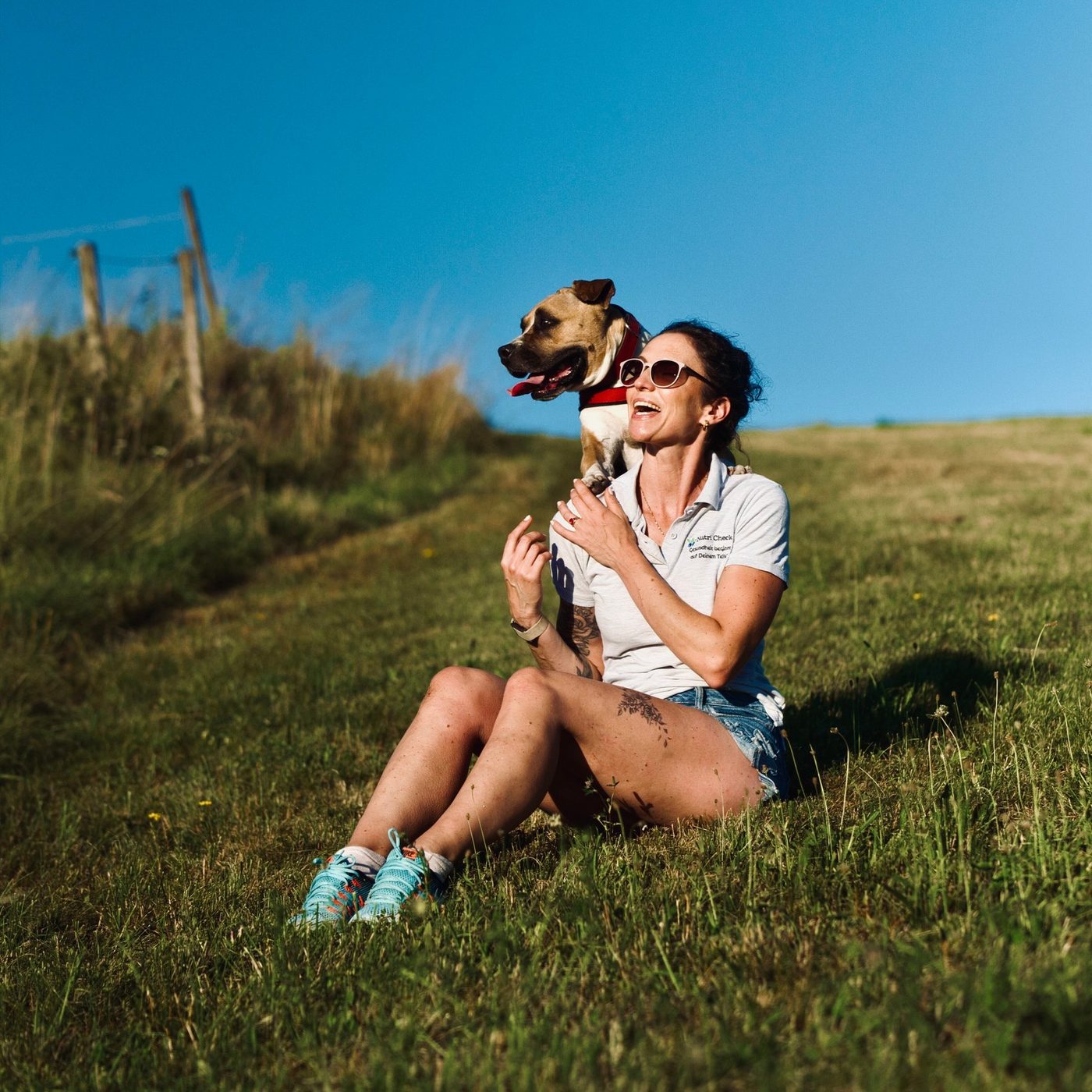 Magdalena Riedl sitzt mit ihrem Hund auf einer Wiese